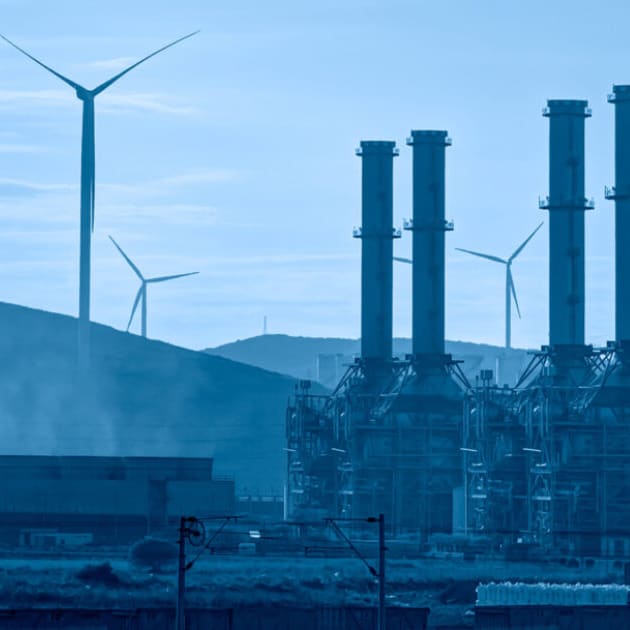 chimneys with wind turbines in the background